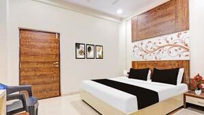 Een hotelkamer met een groot bed, een houten deur en een wand met drie ingelijste foto's.