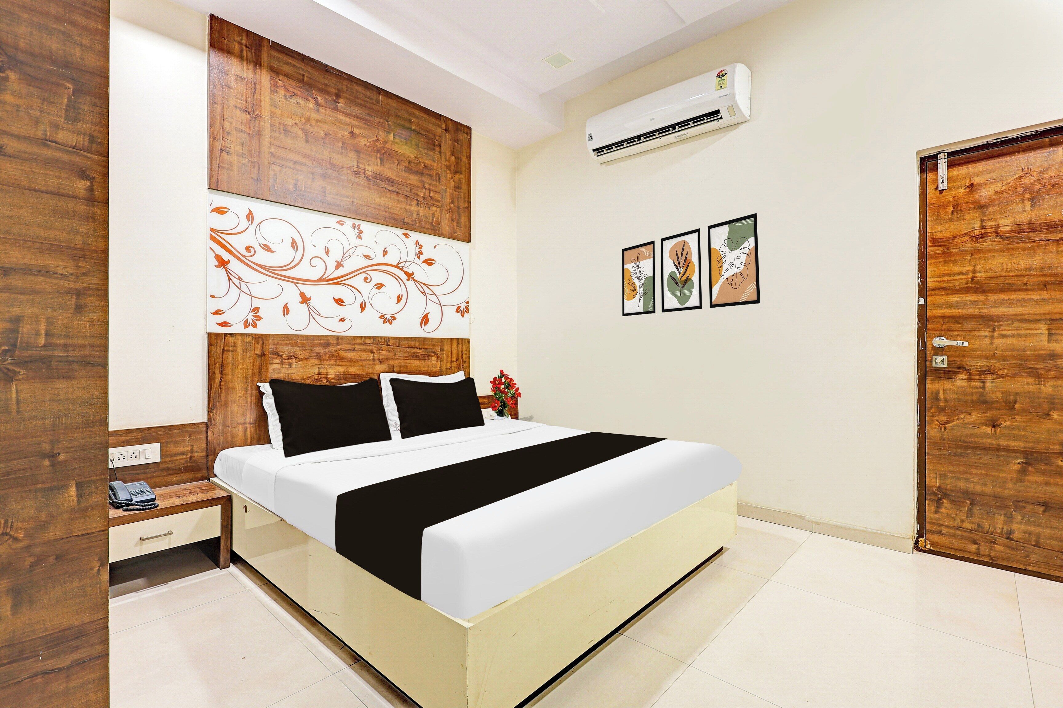 A bedroom with a bed, a nightstand, a wall-mounted air conditioner, and a door.