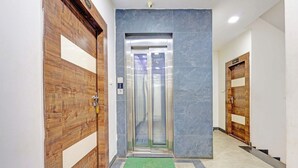 Een lift in een gang met houten deuren aan weerszijden.