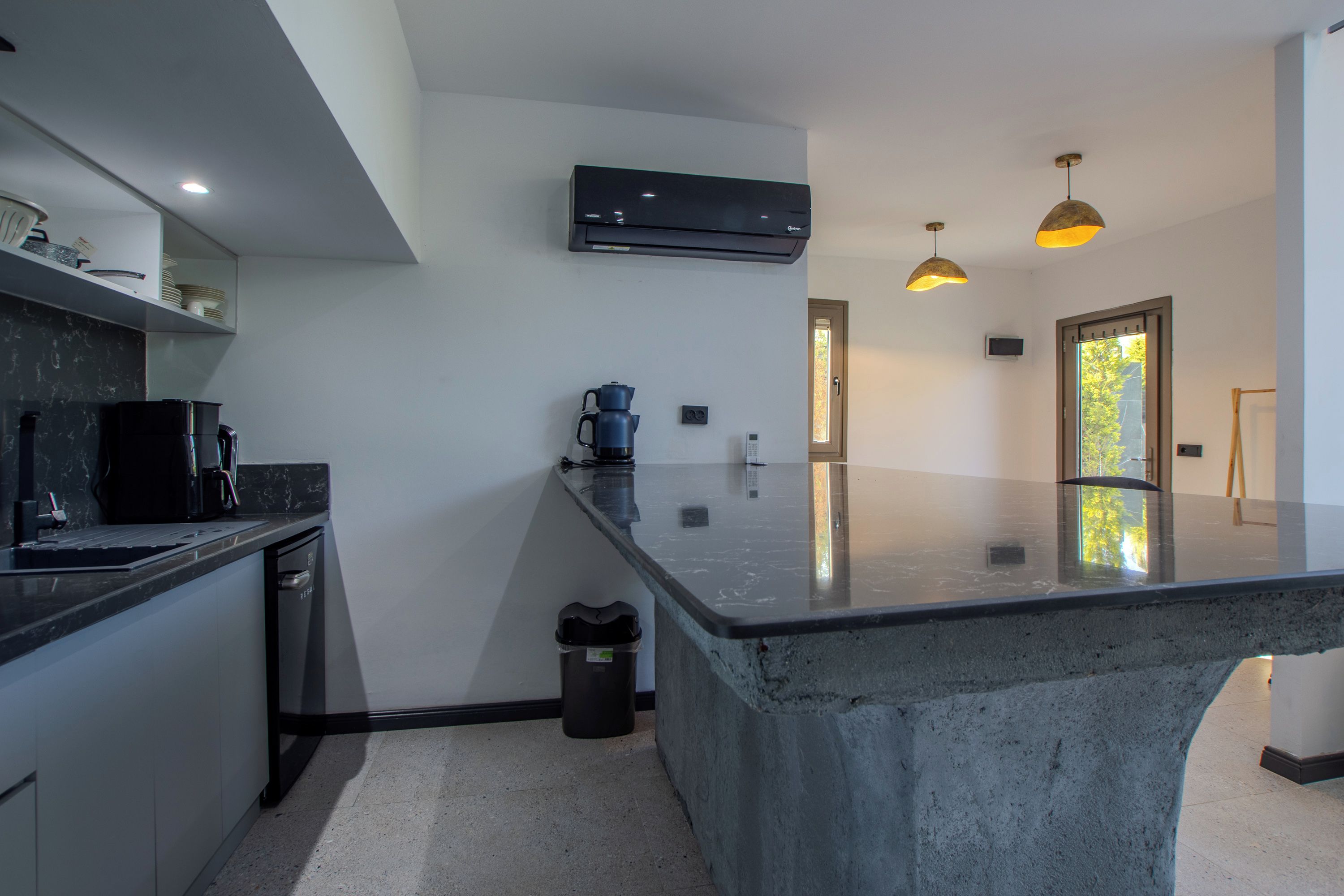 Una cocina moderna con una isla grande, electrodomésticos integrados e iluminación colgante.