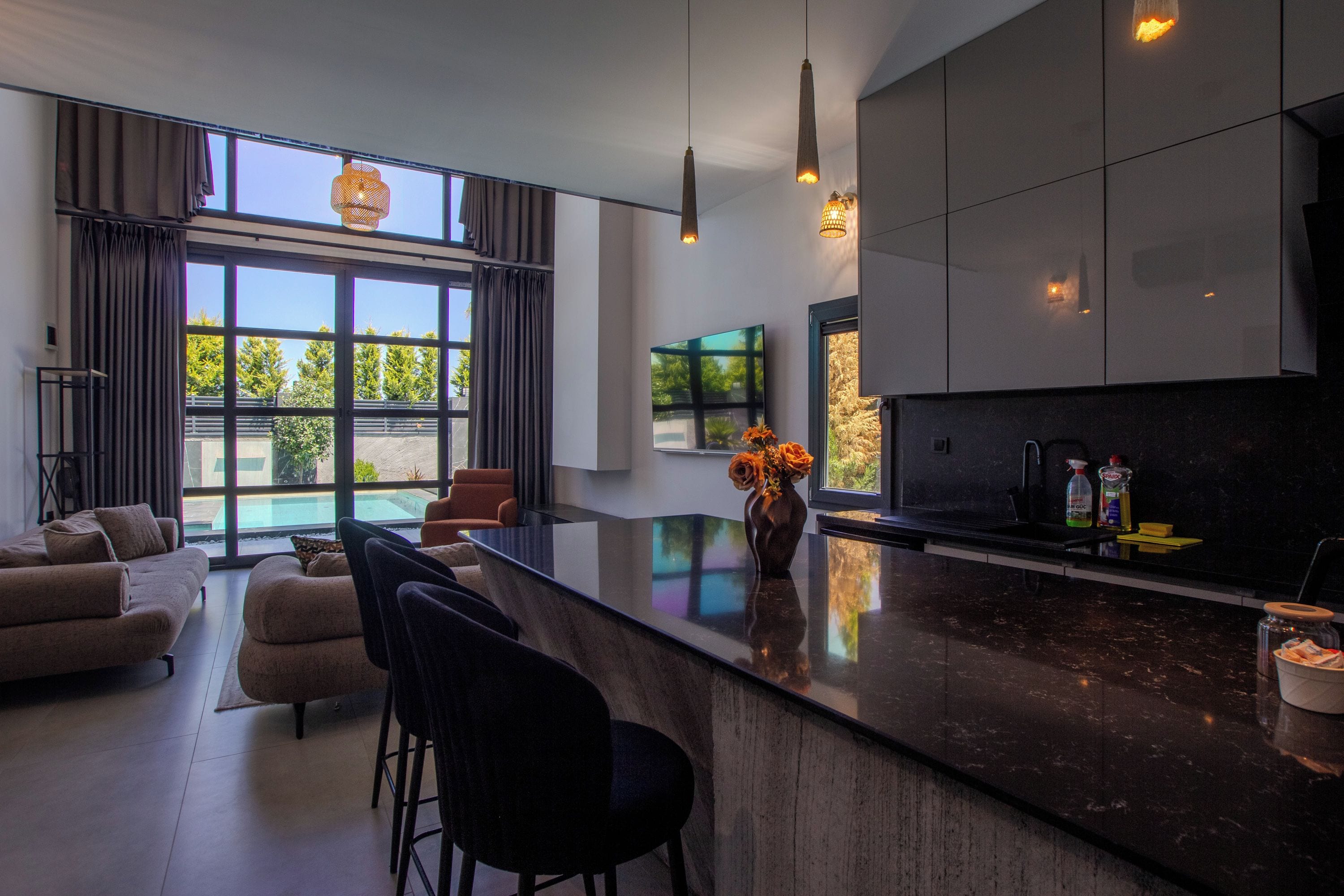 A modern kitchen with a large island, bar stools, and a dining area with a sofa and chairs.