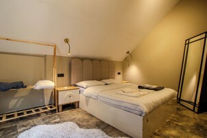 A bedroom with a bunk bed, a bedside table, a lamp, and a large window.