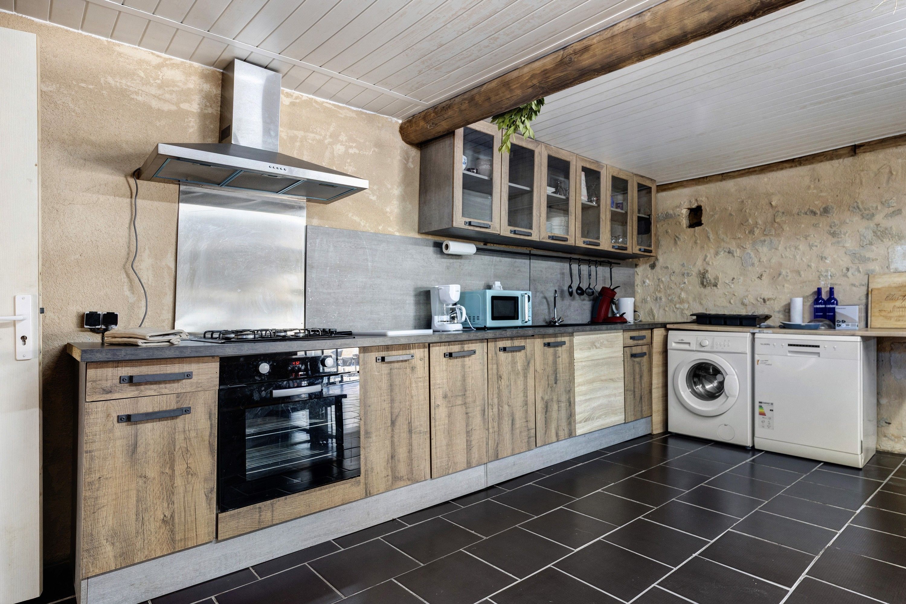 Een moderne keuken met een fornuis, oven, magnetron en wasmachine.