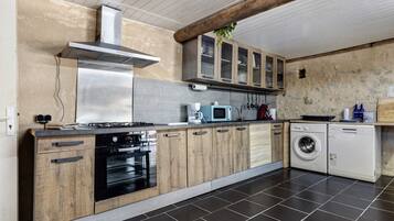 Een moderne keuken met een fornuis, oven, magnetron en wasmachine.