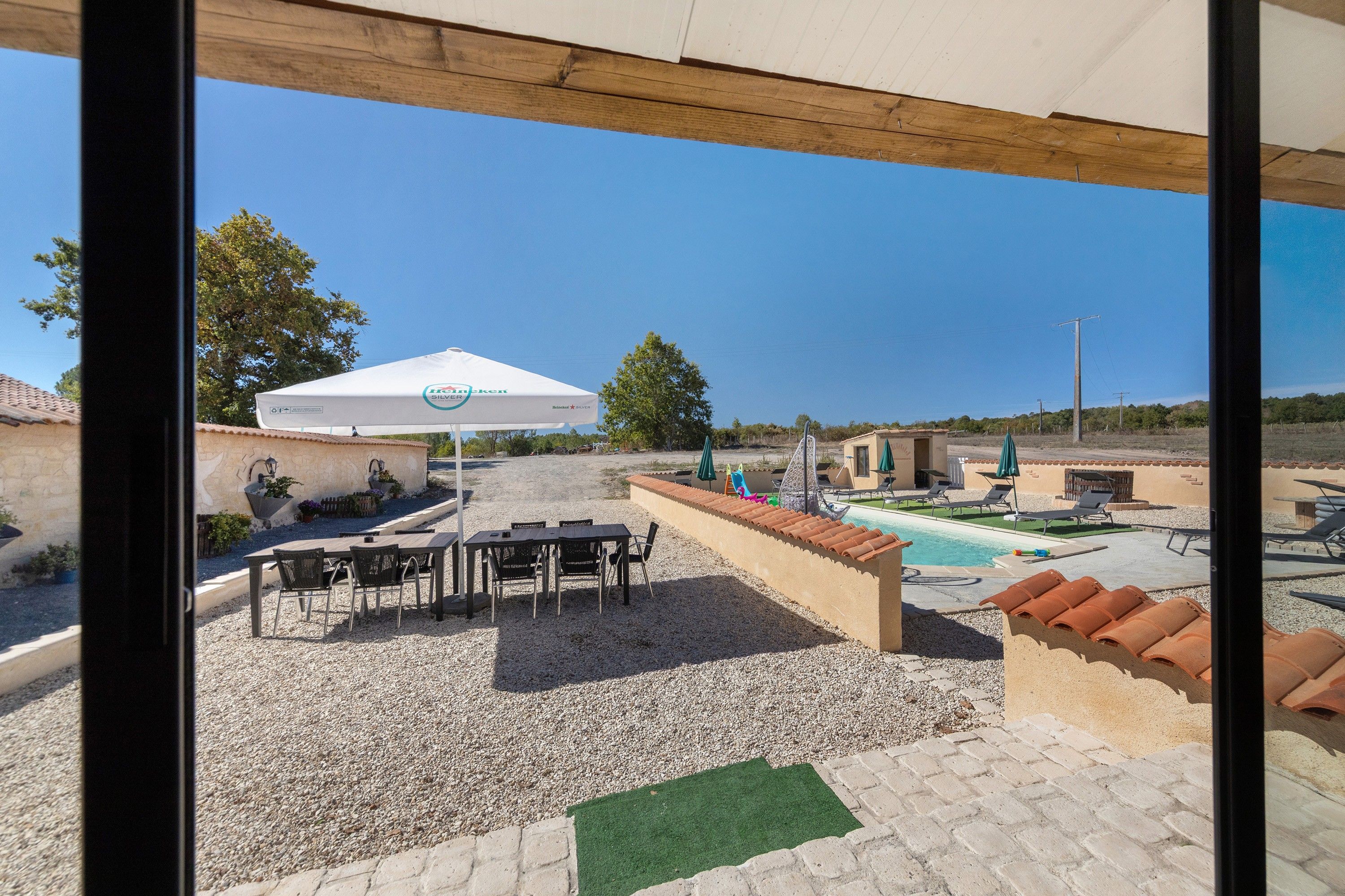 Un espace extérieur aménagé avec des tables et des chaises, un parasol et une piscine.