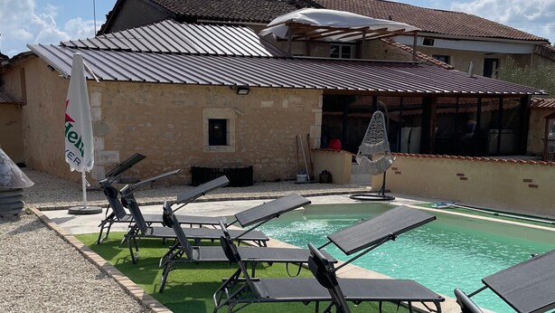 A pool area with lounge chairs and a covered seating area.