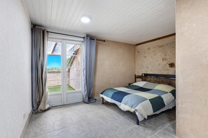 A bedroom with a bed, a window with curtains, a tiled floor, and a ceiling light.
