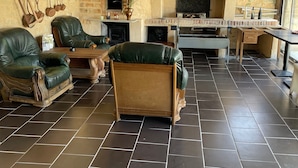 A rustic interior with a fireplace, wooden furniture, and a tiled floor.