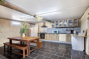 A modern kitchen with wooden cabinets, a dining table, and a bench.