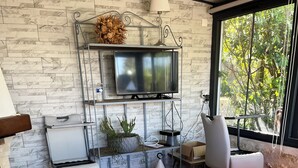 A modern living room with a red sofa, a television mounted on a wall, and a view of greenery outside.