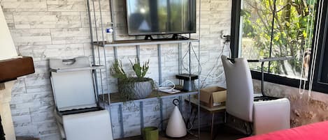 A modern living room with a red sofa, a television mounted on a wall, and a view of greenery outside.