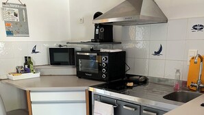 A modern kitchen with a microwave, toaster, and stove. There is a sink and a small countertop with a towel.