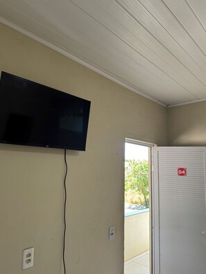 Habitació amb televisió penjada a la paret, una porta amb el símbol de número i una presa elèctrica.