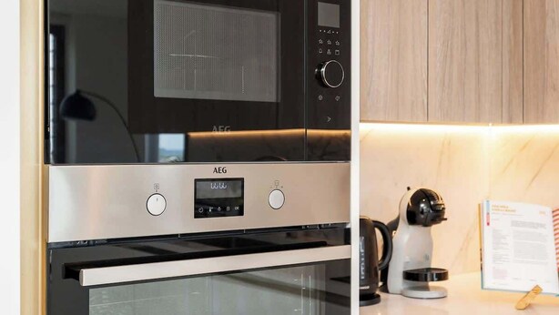 Una cocina moderna con electrodomésticos integrados, incluyendo un microondas y horno, y armarios de madera.