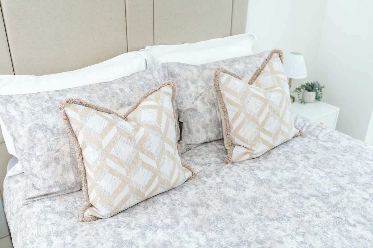 A bed with patterned pillows and a textured bedspread.