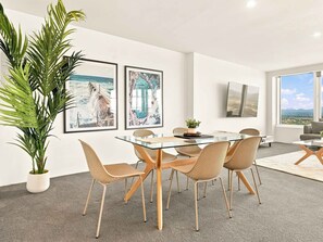 Uma área de refeições moderna com uma mesa de vidro, cadeiras de vime e um vaso de planta.