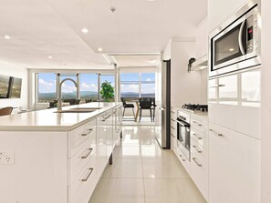 Cozinha moderna com uma ilha grande, eletrodomésticos de aço inoxidável e vista para a cidade.