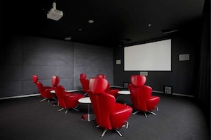 A conference room with red chairs, a projector, and a blank screen. - Sky High Luxury Views | Resort Living |  Parking (Surfers Paradise)