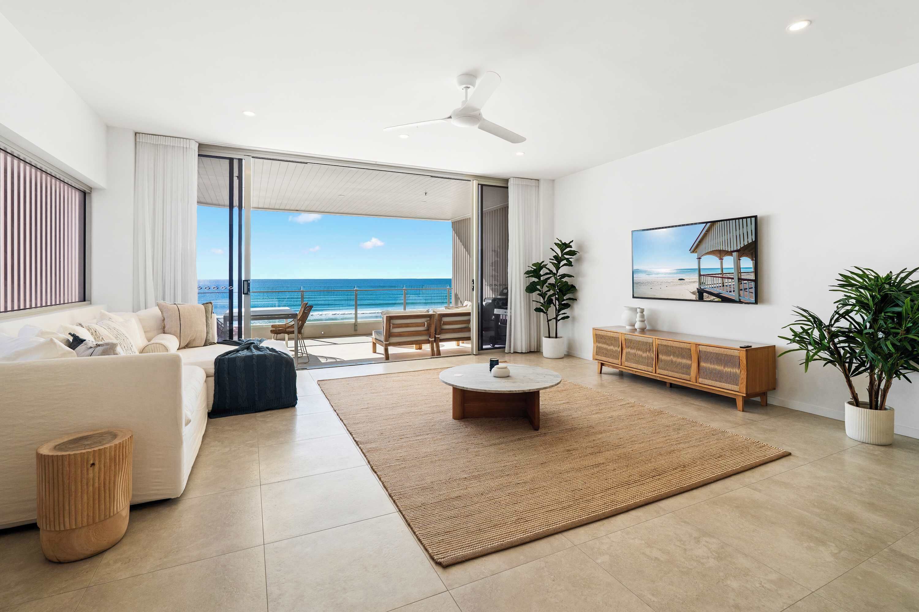 Een moderne woonkamer met een grote schuifpui naar een balkon met uitzicht op de oceaan.