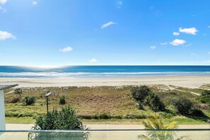 Blick auf einen Strand vom Balkon aus, mit einer Solaranlage, Vegetation und blauem Himmel.