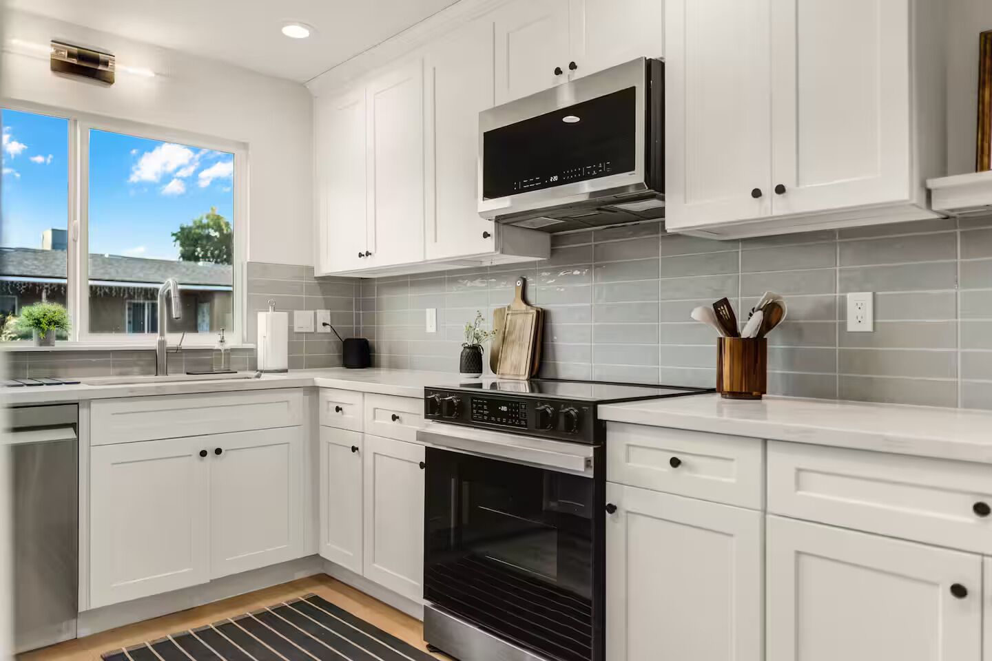 A modern kitchen with white cabinetry, a stainless steel range, and a black oven.