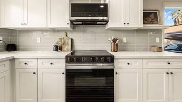 A kitchen with white cabinets, a stainless steel range hood, and a built-in oven.