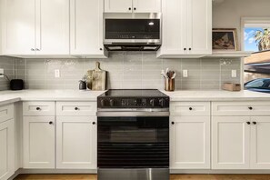 A kitchen with white cabinets, a stainless steel range hood, and a built-in oven.