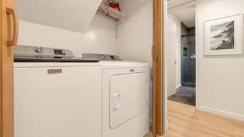 Uma lavanderia com máquina de lavar e secadora Maytag, teto branco e chão de madeira.