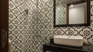 Baño con lavamanos blanco, espejo y ducha con pared de diseño blanco y negro.