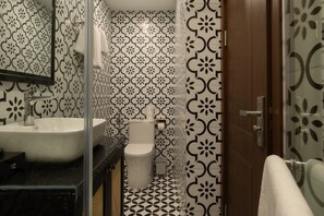 Un baño con lavamanos blanco, inodoro y zona de ducha.