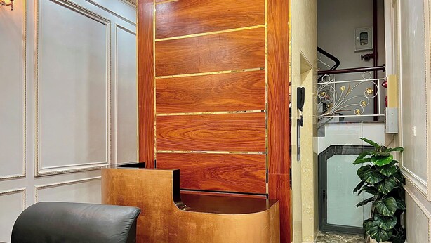 Un interior moderno con un panel de madera, un sillón de cuero negro, piso de mármol y una planta en maceta.