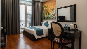 Habitación de hotel con cama, escritorio, silla, un cuadro y vistas al exterior.
