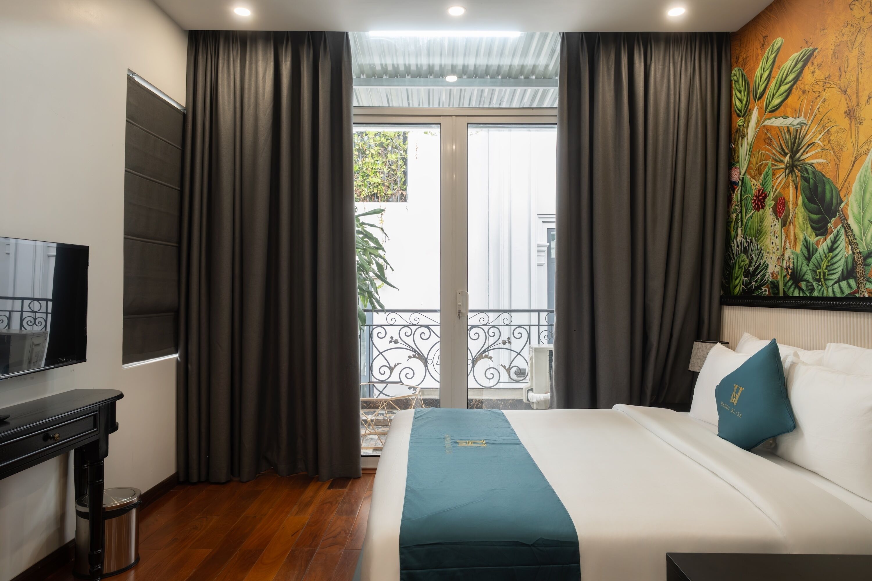 A hotel room with a bed, a TV, a desk, and a balcony with a view.