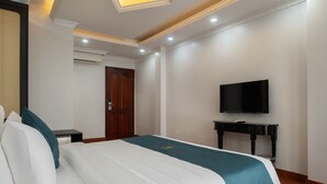 Habitación de hotel con cama, televisor, escritorio y armario.