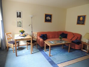 Un salon comprenant un canapé, une table basse, une table à manger avec des chaises et une lampe.