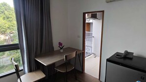 Una habitación pequeña con escritorio, sillas, teléfono y ventana con cortinas.