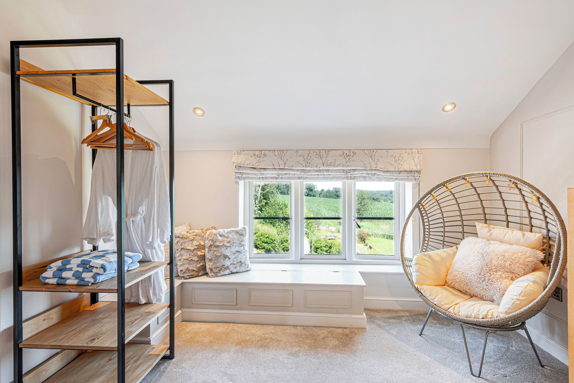 A room with a bed, a hanging chair, a wardrobe, and a window with a view of greenery.