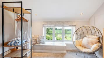 A room with a bed, a hanging chair, a wardrobe, and a window with a view of greenery.