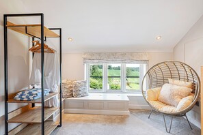 A room with a bed, a hanging chair, a wardrobe, and a window with a view of greenery.