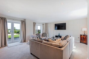 A living room with a sofa, a coffee table, and a flat-screen TV mounted on the wall. - Fairvale House (Northwich)