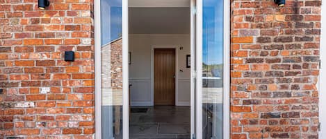 A brick building with a glass door entrance, a wooden door inside, and a star-patterned mat at the entrance.