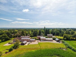 A large estate with multiple buildings, expansive green fields, and a clear sky.