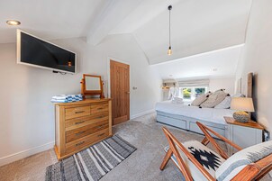 A bedroom with a bed, a dresser, a television, a mirror, and a window.