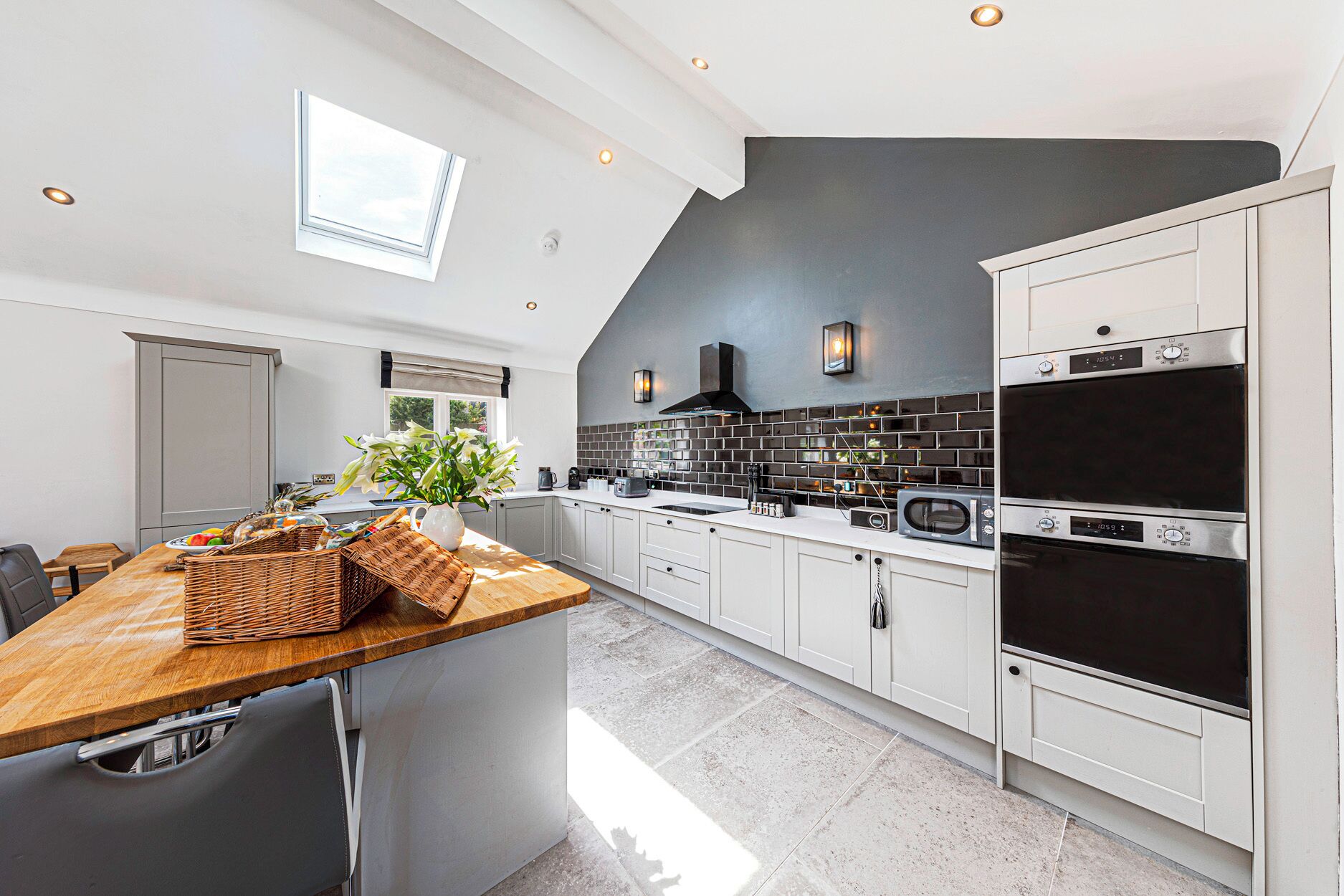 A modern kitchen with white cabinets, a wooden countertop, and a black backsplash.