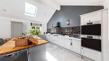 A modern kitchen with white cabinets, a wooden countertop, and a black backsplash.