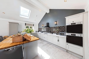Una cocina moderna con armarios blancos, encimera de madera y salpicadero negro.