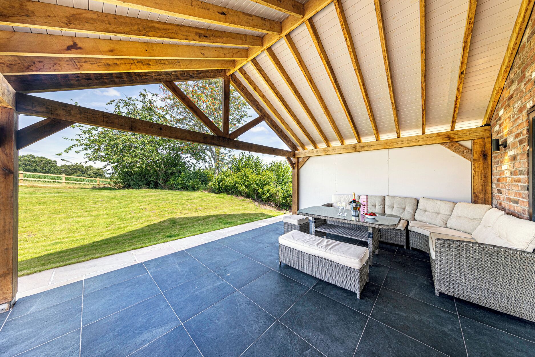 Un patio exterior con techo de madera, una mesa de comedor y un sofá.