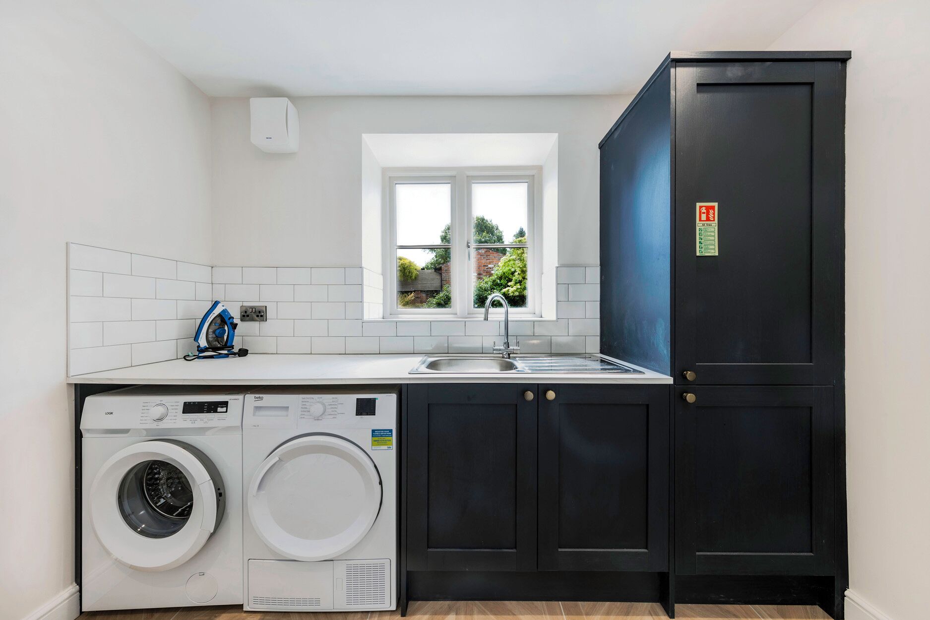 A compact kitchen with a washing machine, a sink, and a window.