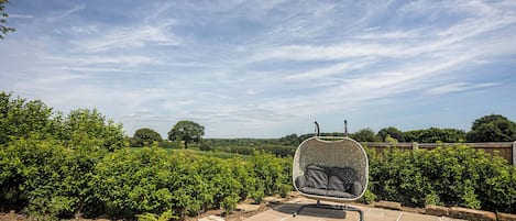 Jardín con zona de estar, que incluye una silla con respaldo tejido y un cojín.
