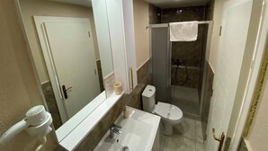 Un baño con un espejo grande, un lavabo, un inodoro y una ducha.